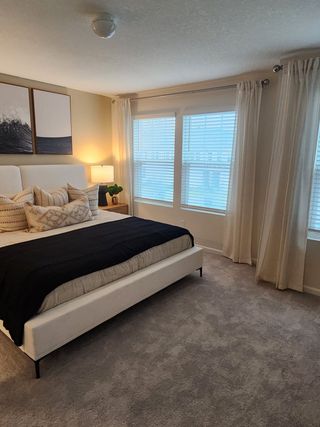 Model Home A cozy bedroom featuring a plush carpet, elegant drapes, and modern artwork that complements the serene atmosphere.
