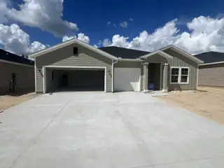 A modern single-story green home with a spacious driveway in Pioneer Ranch: Pioneer Ranch 40's by Lennar (Ocala, FL).