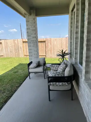 A cozy patio featuring cushioned chairs and a lush lawn, ideal for relaxing and enjoying the outdoors.