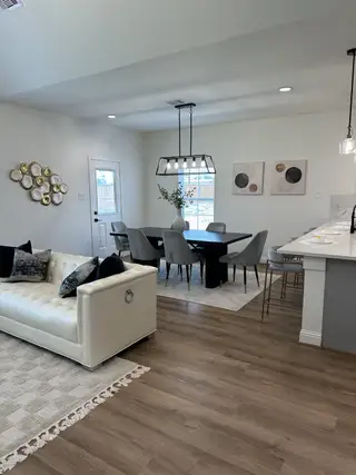 A modern living space with chic decor, featuring a white sofa, elegant dining area, and stylish lighting.