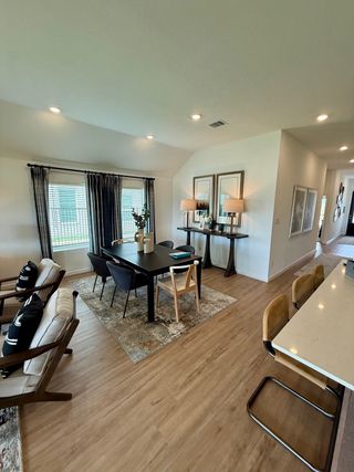 A modern dining area features a sleek table, stylish chairs, and elegant decor with large windows and warm flooring.