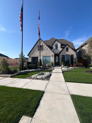 A charming stone home with manicured landscaping in Avondale 45' by Perry Homes (Fate, TX).