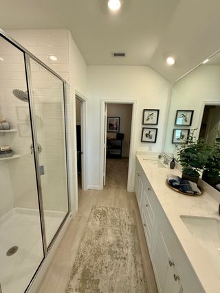 Model Home Stylish bathroom with a spacious shower, elegant vanity, and a cozy rug enhancing its inviting charm.