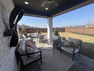 A relaxing covered patio with outdoor seating, a rug, and backyard views in Solterra Texas by Highland Homes (Mesquite, TX).