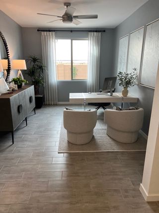 A modern home office with sleek gray tile flooring, cozy chairs, and elegant decor, perfect for productivity and relaxation.