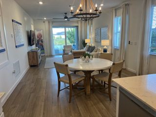 A modern living area with wood flooring, a chic chandelier, and large windows offering natural light.