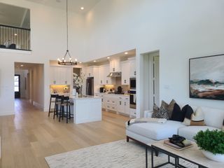 Model Home A spacious open-concept living area featuring a modern kitchen, cozy seating, and elegant lighting.