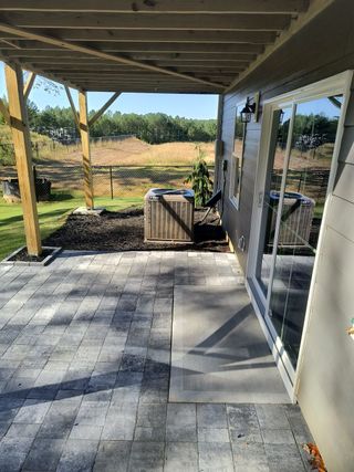 Model Home A cozy patio area with paver stones, sliding glass door, and views of a natural landscape.