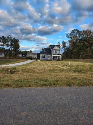 Street view A charming blue home with a long driveway and spacious yard in Olde Place by RiverWILD Homes (Zebulon, NC).