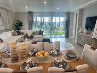 A bright living and dining area with elegant decor, a cozy sectional, large windows, and ample natural light.