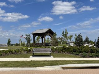 A scenic community park with a charming pavilion, lush greenery, and walking paths in Del Webb Minneola.