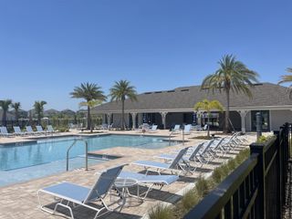 A relaxing pool area surrounded by lush palm trees, perfect for enjoying the sunny weather at Tohoqua Reserve by Pulte Homes (Kissimmee, FL).