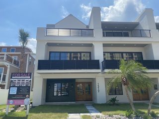 A modern white townhome with sleek black railings in Townhomes on 1st by Benchmark Commercial Group (Jacksonville Beach, FL).