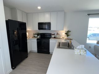 A modern kitchen with sleek black appliances, white cabinets, and a spacious countertop illuminated by soft lighting.