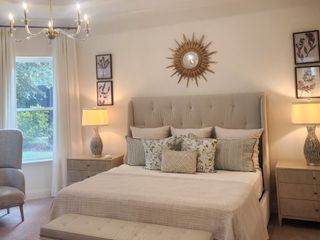 A serene master bedroom with a tufted headboard, gold accents, and soft lighting, creating a peaceful and refined space.