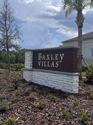 Charming entrance sign for Baxley Villas by Drees Custom Homes in Middleburg, FL, set amid lush landscaping and trees.