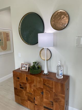 A modern interior with a textured wood console, artistic wall decor, and sleek white lamp, creating a stylish entryway.