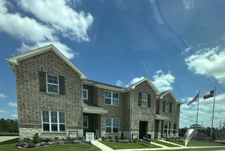 Street view A charming brick townhome with landscaped yard in Seven Oaks Townhomes by HistoryMaker Homes (Tomball, TX).
