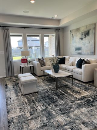 A cozy living room featuring a plush white sofa, abstract art, and large windows overlooking a fenced backyard.