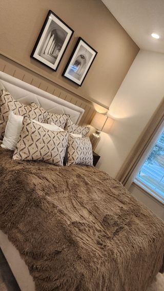 A cozy bedroom with a plush fur bedspread, neutral tones, and elegant framed artwork for a warm and inviting atmosphere.