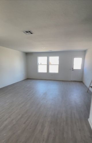 Model Home An open, bright room with light wood flooring, white walls, and large windows.