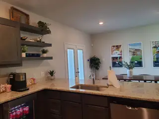 Model Home Modern kitchen with granite countertops, open shelves, and sleek cabinetry, creating a stylish and functional space.