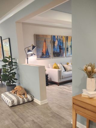 Model Home A cozy living space with modern decor, featuring sailboat artwork, a comfy sofa, stylish lighting, and a playful dog corner.