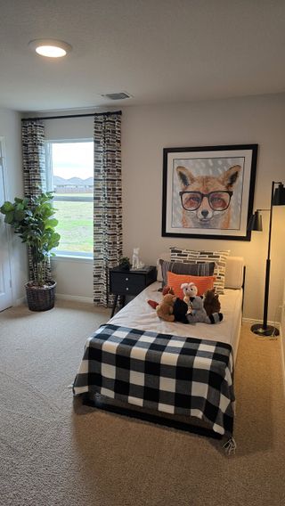 A cheerful kid’s room with a stylish fox-themed accent, a plaid bedspread, and a large window for plenty of natural light.