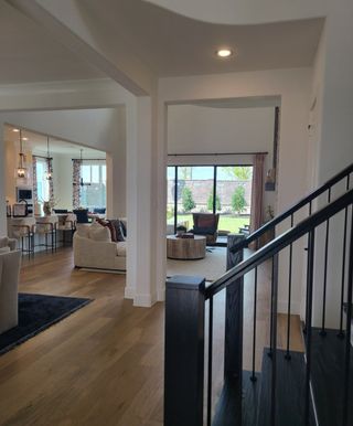 Model Home Spacious open-concept living area with wooden floors, modern seating, and expansive windows overlooking the yard.