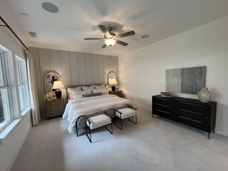 A beautifully decorated bedroom with soft pink bedding, rattan headboard, and large window for natural light.