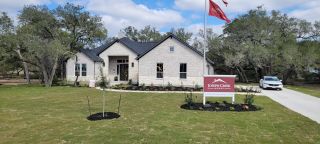 Elegant white stone home with manicured landscaping in Pradera Ridge by Joseph Creek Homes (Floresville, TX).