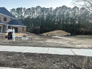 Street view A new brick home under construction in Montvale at Copperleaf by Upright Builders, nestled in a wooded area of Cary, NC.