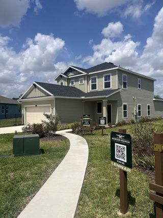 A modern beige home with a manicured lawn in Marion Ranch: Marion Ranch Townhomes by Lennar, located in Ocala, FL.