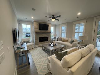A cozy living room featuring a fireplace with a wood accent wall, plush white sofas, and large windows offering plenty of natural light.