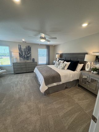 A spacious bedroom with plush carpeting, stylish furniture, and soft lighting, creating a cozy and modern ambiance.