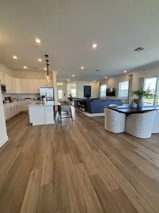 A spacious open-concept living area with sleek hardwood floors, elegant lighting, and a modern kitchen.