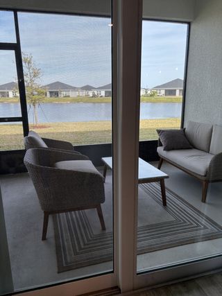 A cozy patio with wicker seating, a sleek table, and a serene water view, perfect for relaxation.