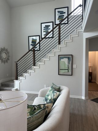A modern living area with a sleek staircase, abstract art, and cozy seating, showcasing stylish decor and neutral tones.