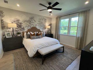 A serene bedroom with a nature-themed accent wall, cozy bedding, and ample natural light.