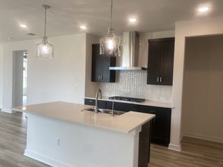 A modern kitchen with dark cabinets, sleek countertops, stainless steel appliances, and elegant pendant lighting.