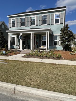 A charming blue home with elegant shutters and a welcoming porch in Midtown at Nexton by Ashton Woods (Summerville, SC).