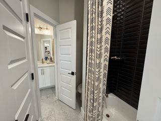 Model Home A modern bathroom featuring sleek black tiles, patterned shower curtain, and stylish vanity with brass fixtures.