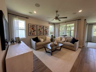Model Home A cozy living room with neutral tones, abstract art, a comfortable sofa, and large windows for natural light.