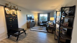A cozy living area with a creative chalkboard, modern shelving, and a plush couch, accented by a large window view.
