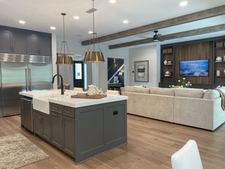 A modern open-concept living area with a sleek kitchen island, elegant lighting, and wood accents.