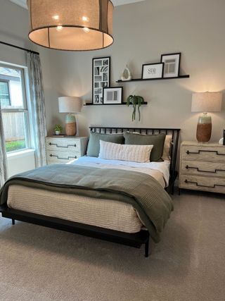 Cozy bedroom with a stylish bed, elegant lighting, and framed artwork; soft hues create a serene atmosphere.