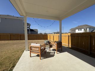 Model Home A cozy patio with wooden chairs and string lights, perfect for outdoor relaxation.
