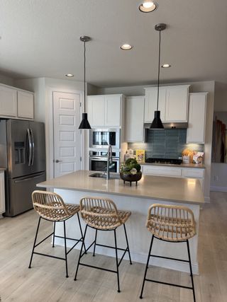 Model Home A modern kitchen with sleek cabinetry, pendant lighting, and a central island with rattan stools.