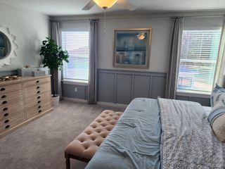 A serene bedroom featuring soft blue accents, a cozy tufted bench, and elegant decor with ample natural light.