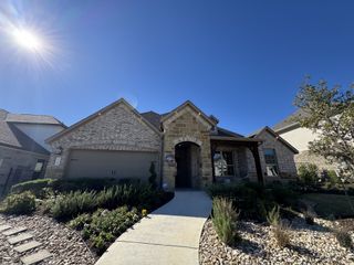 A charming stone-brick home with a manicured garden in Saddleback at Santa Rita Ranch by Pulte Homes (Liberty Hill, TX).